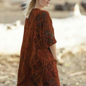 Può includere: Un cardigan all'uncinetto a trama aperta color ruggine, con maniche corte e tasche. Il cardigan presenta un motivo geometrico in tutto il design. Il capo è lungo fino al ginocchio e sembra essere realizzato in un materiale morbido e leggero.