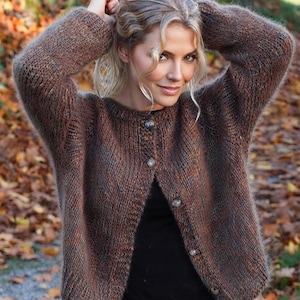 May include: A long-sleeved, button-down cardigan sweater in a variegated brown, rust, and charcoal knit. The garment features a round neckline, ribbed cuffs, and a vertical button placket with five translucent buttons, worn over a plain black shirt.
