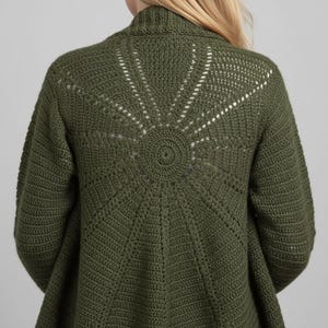 May include: Olive green crochet cardigan with a sunburst design on the back. The open-front sweater features a textured stitch pattern and long sleeves. The back of the cardigan has a circular design with radiating lines.