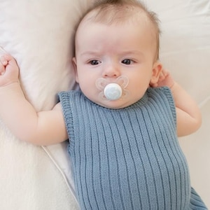 May include: A white ceramic mug with a black handle and the text "But First, Coffee" in a black, handwritten-style font. The mug is on a white surface.