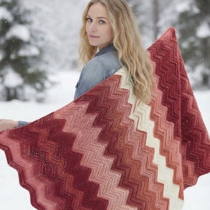 May include: A rectangular crochet blanket featuring a chevron pattern in a gradient of colors ranging from deep burgundy and dark red to lighter shades of coral, peach, and cream. The knit texture is visible throughout the entire fabric surface.