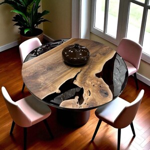Könnte beinhalten: Ein runder Esstisch aus Holz mit dunkler Epoxidharz-Einlage und einer dunkelbraunen Vase. Der Tisch ist von vier rosa Stühlen mit schwarzen Beinen umgeben. Der Durchmesser des Tisches beträgt ca. 122 cm.