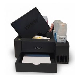 May include: A black Epson printer model with the Epson logo visible. The printer has a tray with white paper and a compartment with ink bottles. The printer's top cover is open, and the Epson logo is also visible on the cover.