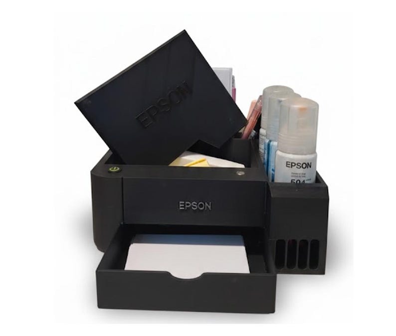 May include: A black Epson printer model with the Epson logo visible. The printer has a tray with white paper and a compartment with ink bottles. The printer's top cover is open, and the Epson logo is also visible on the cover.