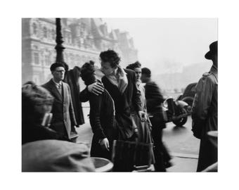 May include: Black and white photograph of a couple kissing in a public space. The image captures a moment of intimacy amidst a crowd, with architectural details in the background. The scene is set in a European city.