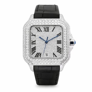 May include: A luxury wristwatch with a square, diamond-encrusted face and bezel. The watch features black Roman numerals, blue hands, and a date display. It has a black leather strap and a silver-coloured case. The watch is a statement piece.