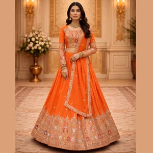May include: An orange lehenga, a traditional Indian garment, featuring intricate embroidery along the hem and bodice. The long-sleeved top and dupatta are adorned with matching embellishments. The outfit is a vibrant, festive ensemble.
