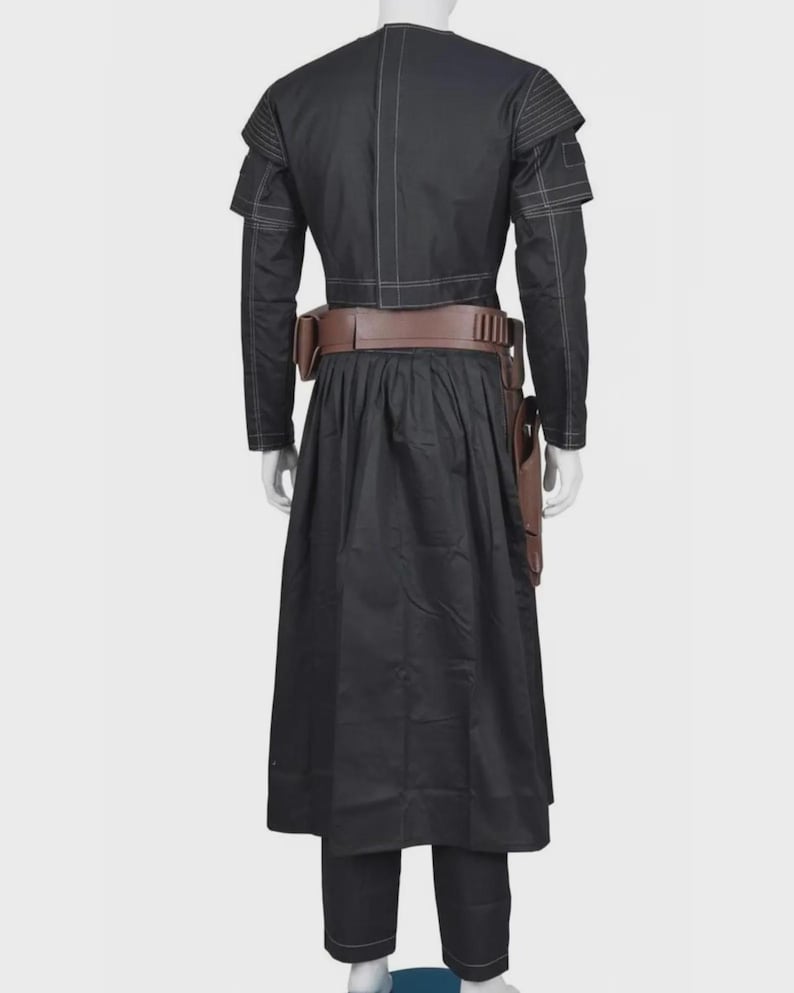 Pode incluir: Um casaco preto de manga comprida com costuras brancas, combinado com uma saia e cal&ccedil;as pretas a condizer. Um cinto utilit&aacute;rio castanho largo com um coldre &eacute; usado &agrave; volta da cintura. O casaco apresenta ombros estruturados e um design.