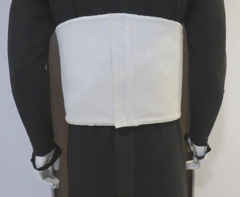 May include: A wide, white, rectangular abdominal support belt worn over a black long-sleeved garment. The belt features a central vertical seam and a smooth, solid white fabric construction that wraps around the midsection of the torso.