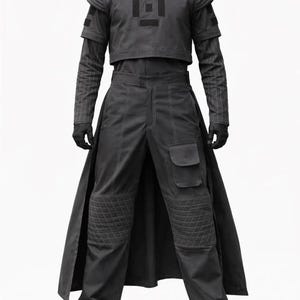 May include: A dark grey ensemble consisting of a cropped short-sleeve top with a central square emblem, layered over a pinstriped long-sleeve shirt. The matching trousers feature a long back panel, quilted knee patches, and a cargo pocket.