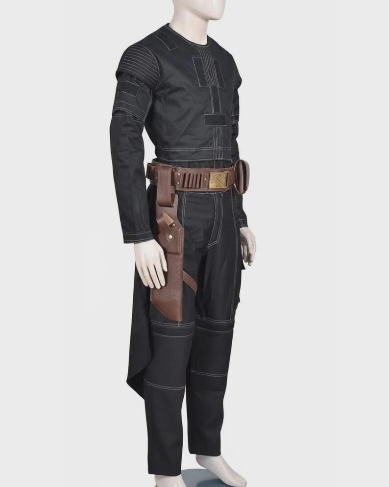 Pode incluir: Um conjunto de camisa de manga comprida e cal&ccedil;as pretas com costuras brancas, detalhes canelados nos ombros e um cinto utilit&aacute;rio de couro castanho com coldre e fivela met&aacute;lica, exibido num manequim sobre um fundo neutro.