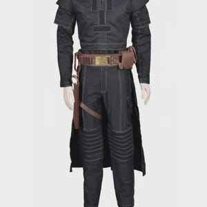 Pode incluir: Um conjunto preto de camisa de manga comprida e cal&ccedil;as com costuras brancas em contraste, pain&eacute;is canelados nos ombros e joelhos, e um cinto utilit&aacute;rio castanho com coldre e bolsa, exibido num manequim branco.