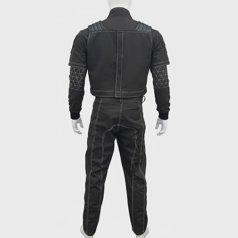 May include: A black two-piece outfit consisting of a jacket and trousers. The jacket features shoulder padding, a central vertical seam, and white contrast stitching. The sleeves have a geometric triangular pattern and ribbed cuffs. The pants feature white vertical seams.