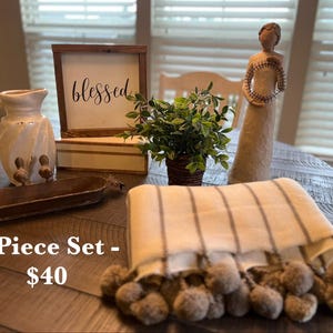 May include: A white ceramic mug with a black handle and the text "But First, Coffee" in a black, bold font. The mug is on a white surface.