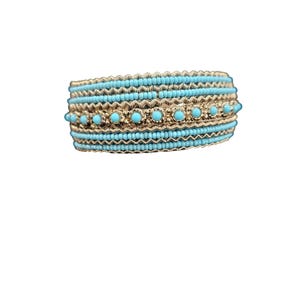 May include: A gold-toned bracelet with turquoise beads and accents. The bracelet features multiple rows of small turquoise beads, interspersed with gold-colored bands and larger turquoise stones, creating a textured and layered design.