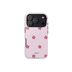 Peut inclure: Coque de téléphone rose ornée d'un motif de fleurs de cerisier rouges. L'étui présente un module de caméra noir et le nom de la marque "AMORVA" imprimé en bas.