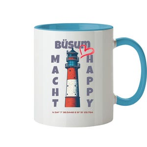 Può includere: Tazza in ceramica bianca con interno e manico blu. La tazza presenta una grafica di faro con le parole "BÜSUM MACHT HAPPY" e un cuore rosso. Le coordinate sono stampate in basso.
