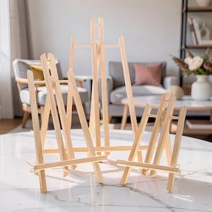 Könnte beinhalten: Eine weiße Keramik-Tasse mit schwarzem Henkel und dem Text "But First, Coffee" in schwarzer, handschriftlicher Schrift. Die Tasse steht auf einer weißen Oberfläche.