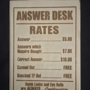 May include: A rectangular light-colored wooden sign with a dark brown laser-engraved text titled ANSWER DESK RATES. It lists prices for various interactions, including Answer $5.00, Answers which Require thought $7.00, Correct Answer $10.00, Cussed Out FREE, and Knocked TF Out FREE, plus a note about dumb looks and eye rolls.
