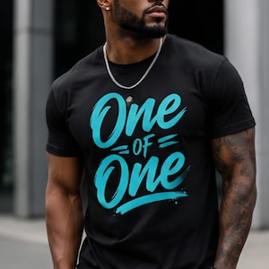 May include: A black short-sleeved t-shirt featuring the text One of One printed in a bright cyan blue brush-stroke font across the chest. The garment has a crew neckline and a standard fit, showcasing a bold graphic design on the front.