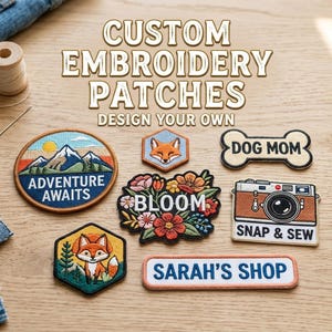 May include: A selection of custom embroidered patches, featuring designs such as a mountain landscape, a fox, floral patterns, and a camera. The patches are displayed on a wooden surface.