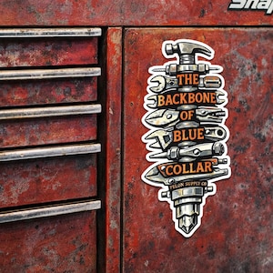 Könnte beinhalten: Ein Aufkleber mit einer vertikalen Anordnung von Werkzeugen, darunter Hammer, Schraubenschlüssel und Zange. Der orangefarbene Text lautet "THE BACKBONES OF BLUE COLLAR". Der Aufkleber befindet sich auf einer verwitterten, roten Metalloberfläche.