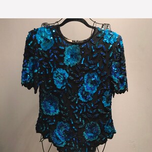 May include: A black sequined top with a floral design featuring blue and teal sequins.