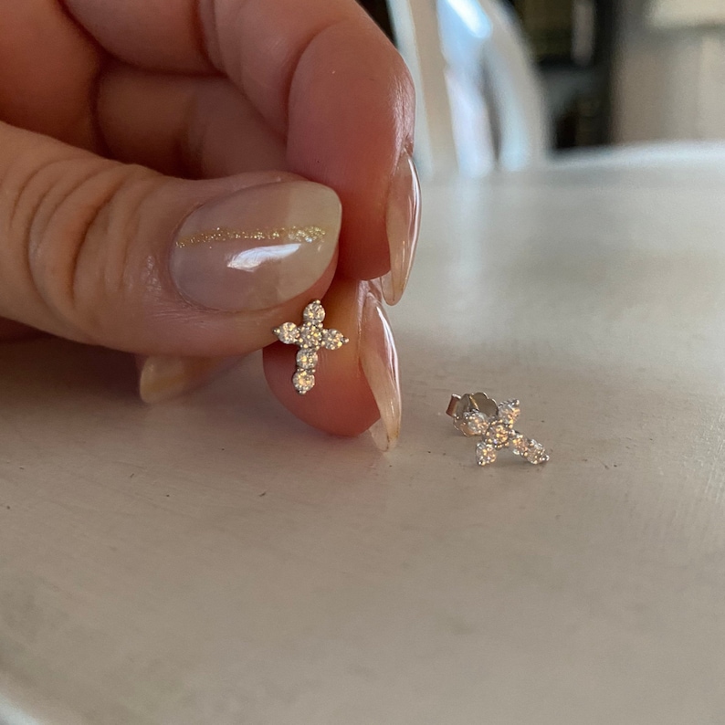 May include: A pair of silver cross earrings with small clear cubic zirconia stones.