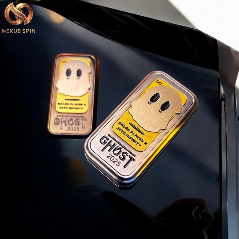 May include: Two rectangular metal Ghost 2025 collectibles with a gold ghost design on a yellow background. The collectibles have the text "HALOO PLAYER X ZETE INFINITY" and are on a reflective black surface.
