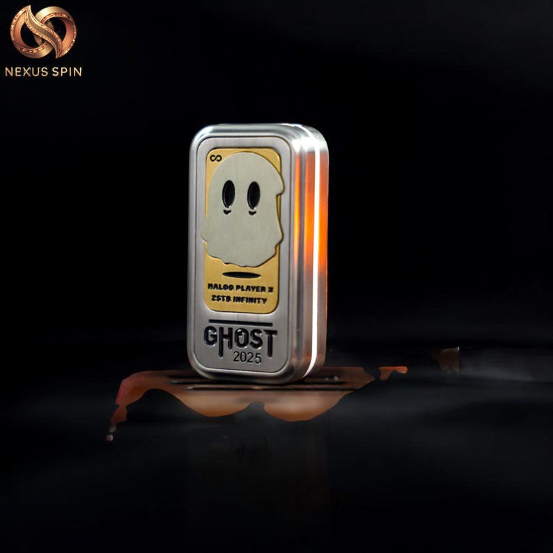 May include: A silver and gold rectangular fidget spinner with a ghost design. The ghost has two black eyes and a curved mouth. The text "GHOST 2025" is at the bottom. The top left corner has the Nexus Spin logo.