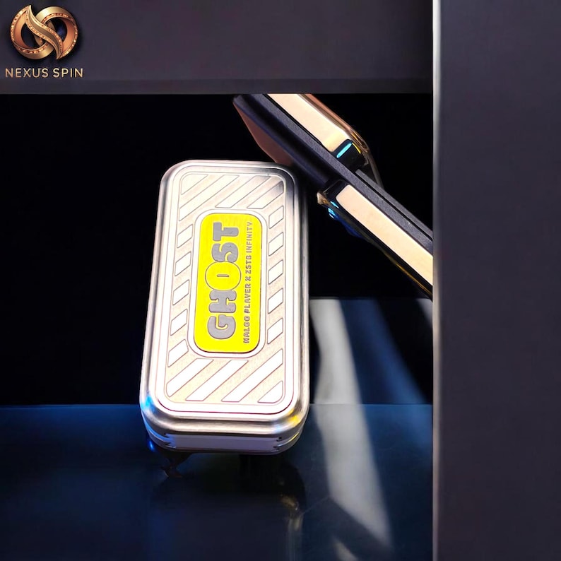 May include: A silver and yellow rectangular device with the word "GHOST" in yellow, and the text "MALOO PLAYER X 25TB INFINITY". The device is next to a gold and black object. The Nexus Spin logo is in the upper left corner.