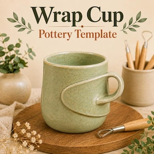 May include: A sage green ceramic mug with a speckled finish and a unique wrap-around handle design. The text "Wrap Cup Pottery Template" is displayed above the mug. The mug sits on a round wooden board alongside pottery tools and greenery.