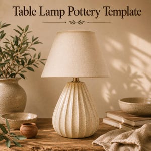 Op de afbeelding: Een tafellamp met een gespikkelde, geribbelde keramische voet en een beige stoffen kap. De tekst "Table Lamp Pottery Template" staat bovenaan. De lamp heeft een messingkleurige hals en staat op een houten ondergrond met ander aardewerk.