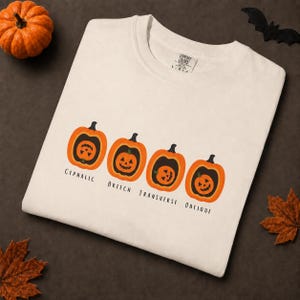 Puede incluir: Una camiseta de manga corta color crema con un gráfico de cuatro calabazas naranjas. Debajo de cada calabaza, el texto dice CEPHALIC, BREECH, TRANSVERSE y OBLIQUE. La camiseta tiene una etiqueta de la marca Comfort Colors impresa en el cuello.