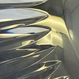 May include: Close-up of a crystal object with a series of sharp, pointed, leaf-like shapes. The crystal reflects light, creating a play of colors and highlights. The overall effect is one of elegance and sophistication.