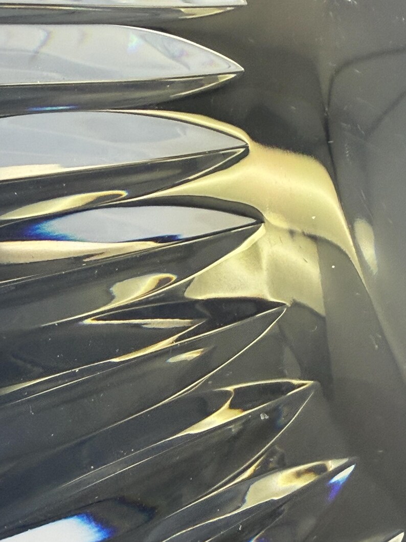 May include: Close-up of a crystal object with a series of sharp, pointed, leaf-like shapes. The crystal reflects light, creating a play of colors and highlights. The overall effect is one of elegance and sophistication.