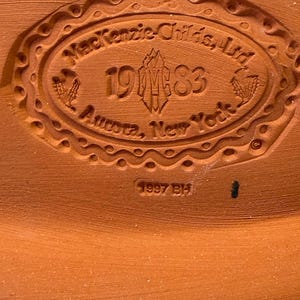Puede incluir: Una base de cer&aacute;mica de color terracota con un sello ovalado en relieve que dice MacKenzie-Childs, Ltd, 1983, Aurora, New York, con un logotipo central y espigas de trigo. Debajo del &oacute;valo, el texto 1997 BH est&aacute; grabado en la arcilla.