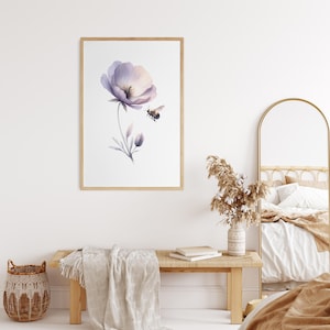 Puede incluir: Impresión en acuarela enmarcada con una delicada flor morada y una abeja. La obra de arte tiene un marco de madera clara y se exhibe en una habitación luminosa y espaciosa. La impresión añade un toque de decoración inspirada en la naturaleza.
