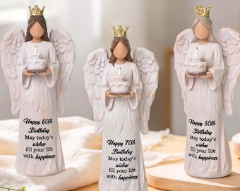 May include: Three angel figurines wearing gold crowns and holding small birthday cakes. Each angel has white wings and a long white gown printed with birthday messages for 60th, 70th, and 80th birthdays, including the text: May today's wishes fill your life with happiness.
