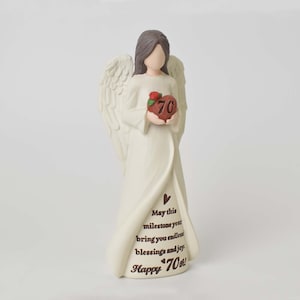May include: A cream-colored angel figurine with brown hair and large wings, holding a red heart with the number 70 and a small rose. The dress features the text: May this milestone year bring you endless blessings and joy. Happy 70th!