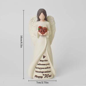 May include: A cream-colored angel figurine with brown hair, holding a red heart with the number 70 and a small green leaf. The base features the text: May this milestone year bring you endless blessings and joy. Happy 70th! Height is 6.3 inches.