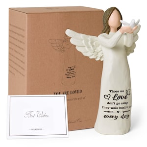 Pu&ograve; includere: Una statuetta di angelo color crema con capelli castani e ali spiegate che tiene una colomba bianca. La veste presenta il testo nero: Those we love don't go away they walk beside us every day. Include una scatola marrone e un biglietto Best Wishes.