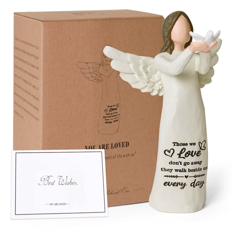 Pu&ograve; includere: Una statuetta di angelo color crema con capelli castani e ali spiegate che tiene una colomba bianca. La veste presenta il testo nero: Those we love don't go away they walk beside us every day. Include una scatola marrone e un biglietto Best Wishes.