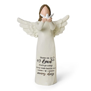 Pu&ograve; includere: Una statuetta di angelo color crema con capelli castani e ali spiegate, che tiene in mano una piccola colomba bianca. La veste presenta il testo nero: Those we Love don't go away they walk beside us every day, con icone di cuori e farfalle.