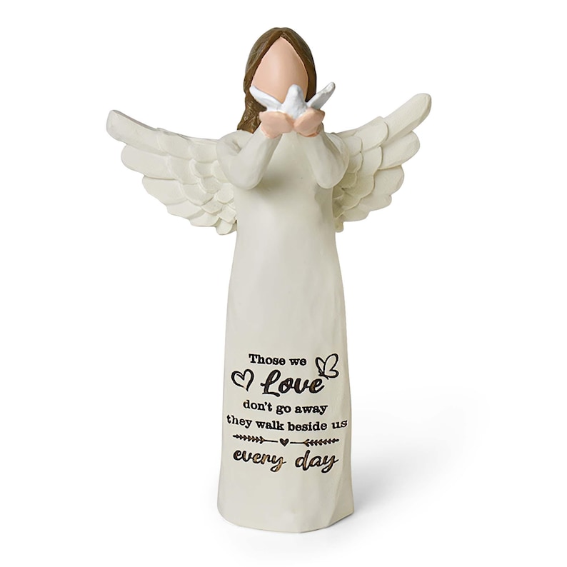 Pu&ograve; includere: Una statuetta di angelo color crema con capelli castani e ali spiegate, che tiene in mano una piccola colomba bianca. La veste presenta il testo nero: Those we Love don't go away they walk beside us every day, con icone di cuori e farfalle.