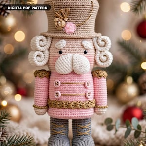 May include: A crochet nutcracker doll featuring a tan top hat with a gold cord and pink flower, white curly hair, a pink jacket with four buttons, and gray boots. The text DIGITAL PDF PATTERN is visible in the upper left corner.
