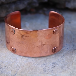 Pu&ograve; includere: Un ampio bracciale a polsino in rame con una texture martellata e quattro piccoli rivetti rotondi. Il design aperto consente di indossarlo facilmente. Il bracciale ha un colore marrone-rossastro caldo ed &egrave; adatto all'uso quotidiano.