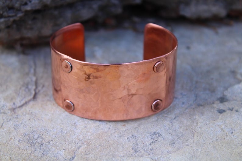 Pu&ograve; includere: Un ampio bracciale a polsino in rame con una texture martellata e quattro piccoli rivetti rotondi. Il design aperto consente di indossarlo facilmente. Il bracciale ha un colore marrone-rossastro caldo ed &egrave; adatto all'uso quotidiano.