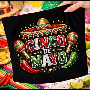 Peut inclure: T-shirt noir avec un motif Cinco de Mayo. Il présente un sombrero, des maracas, des piments et le texte "Cinco de Mayo" en rouge, blanc et vert, avec des accents dorés et des étoiles.