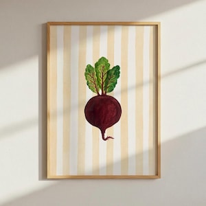 Könnte beinhalten: Ein gerahmter Kunstdruck mit einer Aquarellillustration einer Rote Bete. Die Rote Bete hat eine tiefrote Farbe mit grünen Blättern, vor einem Hintergrund aus vertikalen cremefarbenen und hellgelben Streifen. Der Rahmen ist helles Holz.